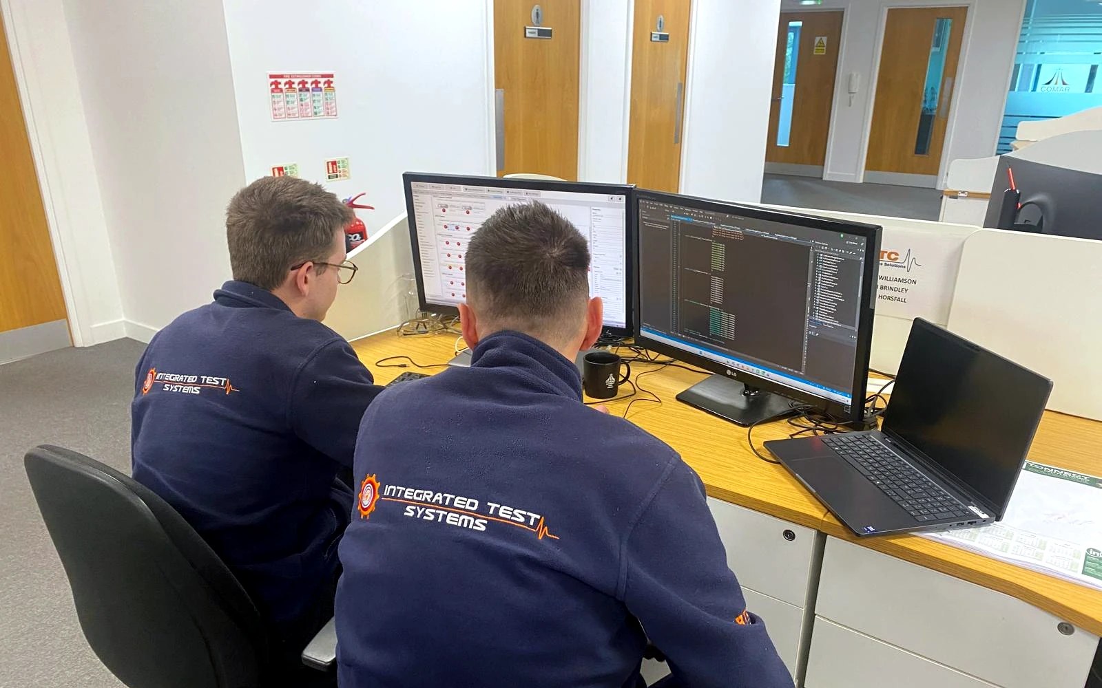 RTC and Integrated Test Systems engineers developing control software and HIL test sequences at a dual-monitor workstation